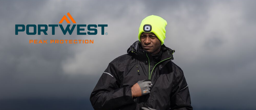 Image of a worker in black work clothes. The man is wearing gloves and a yellow cap with a built-in LED light. In the background, dark clouds and a foggy landscape are visible.