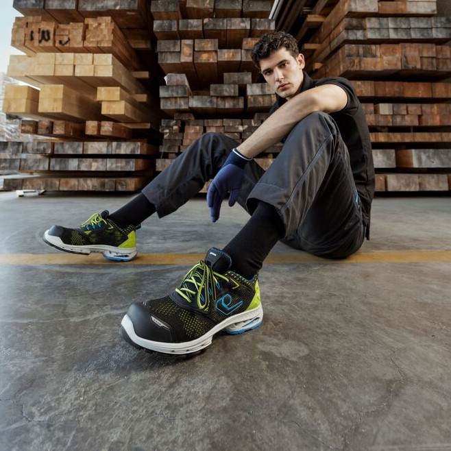 Young worker sitting on the ground in front of stacked wood.