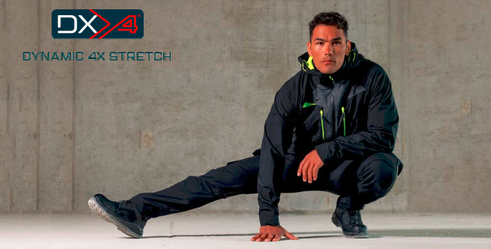Man in black, sporty workwear with neon accents crouching in front of a gray concrete wall. Top left is the 'DX4 Dynamic 4X Stretch' logo.