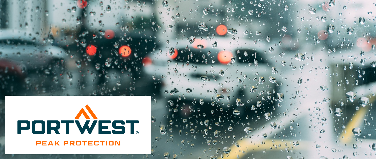 Rain-soaked street with cars photographed through a window covered in raindrops. In the bottom left corner is the blue and orange Portwest logo on a white background.