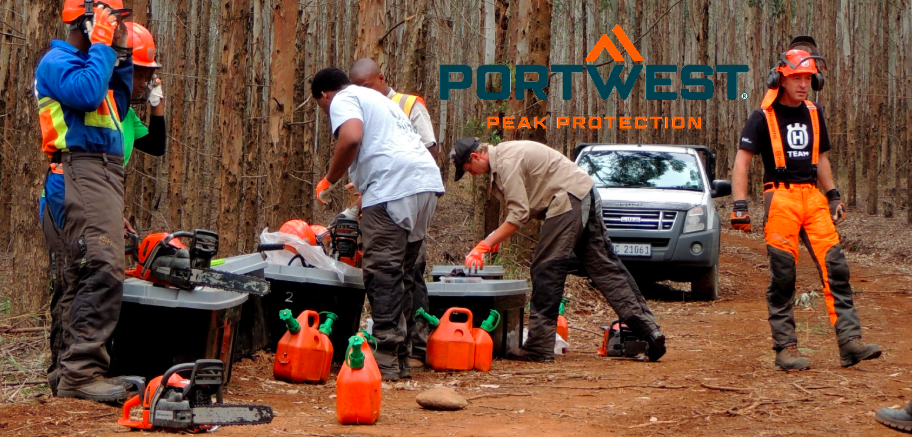 Forest workers in a clearing preparing for chainsaw work. The manufacturer's logo, Portwest, in blue and orange, is centered above the scene.