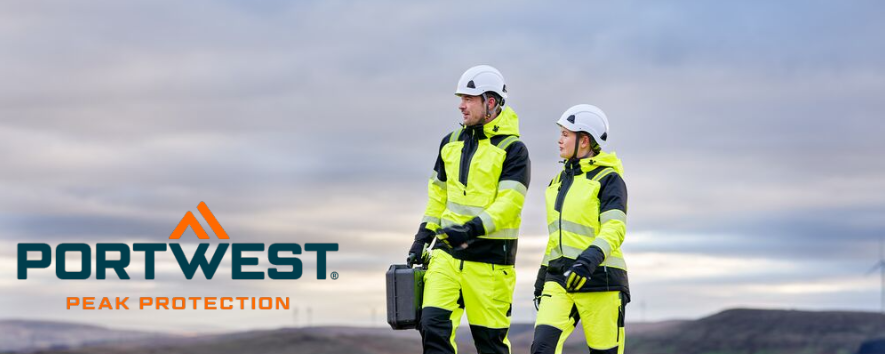 The image shows a man and a woman in yellow workwear and white hard hats. They are walking on a gravel path. In the background, you can see a range of hills and a blue sky with clouds. The blue and orange Portwest logo is located in the lower left corner.