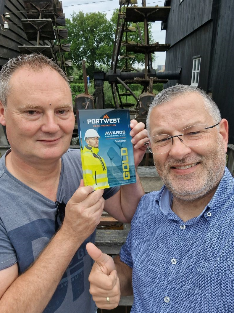 Sjoerd Kusters and Patrick Kits against a rural background. The men smile at the camera, Sjoerd holds the gold plaque in his hands, Patrick gives his right thumb up.